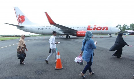 Penumpang berjalan di samping pesawat Lion Air jenis Boeing 737-900 ER, registrasi PK-LGY dengan nomor penerbangan JT633 yang terparkir setelah di 