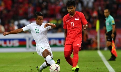 Pemain timnas Indonesia Febri Hariyadi (kiri) mencoba merebut bola dari pemain timnas Singapura Muhammad Yasir Hanapi dalam penyisihan grub B Piala AFF 2018 di Stadion Nasional Singapura, Jumat (9/11/2018).