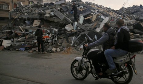 Warga melintasi bangunan yang hancur akibat serangan Israel ke Kota Gaza, Rabu (12/11).