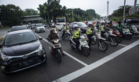 Sejumlah anggota Satlantas Polres Metro Jakarta Pusat saat melakukan sosialisasi tilang elektronik kepada masyarakat pengguna kendaraan bermotor di persimpangan Bundaran Patung Kuda, Jakarta, Senin (26/11/2018).