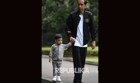 Presiden Joko Widodo menggandeng cucu Jan Ethes di kawasan Istana Bogor, Jawa Barat, Sabtu (8/12). 