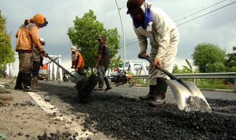 Pekerja mengerjakan pengaspalan jalan rusak di jalur Pantura Tegal, Jawa Tengah, Sabtu (8/12/2018).