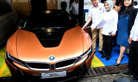 Menteri ESDM Ignasius Jonan (kiri) didampingi Dirut Pertamina Nicke Widyawati (tengah) dan VP of Corporate Communication BMW Group Indonesia Jodie O'tania (kanan) melakukan pengisian mobil listrik BMW i8 Roadster saat peluncuran Green Energy Station (GES) Pertamina di Jakarta, Senin (10/12/2018).