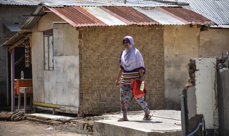 Seorang perempuan melintas dekat bangunan Hunian Sementara (Huntara) yang dibangun warga korban gempa secara swadaya di Desa Kerandangan, Kecamatan Batulayar, Lombok Barat, NTB, Senin (10/12/2018). 