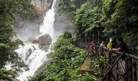 Pengunjung menikmati keindahan air terjun di kawasan wisata alam Geopark Curug Cimarinjung, Ciemas, Kabupaten Sukabumi, Jawa Barat, Minggu (16/12/2018). 