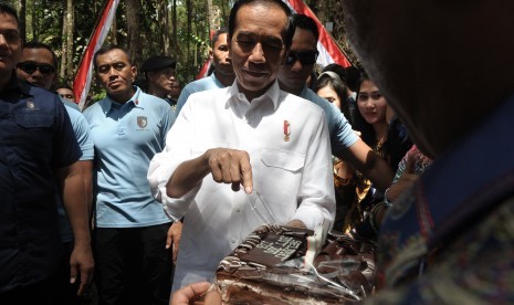 Presiden Joko Widodo (tengah) menerima kejutan kue dari warga usai Penyerahan Surat Keputusan (SK) Perhutanan Sosial di Taman Hutan Pinus Kenali, Kota Jambi, Minggu (16/12/2018).