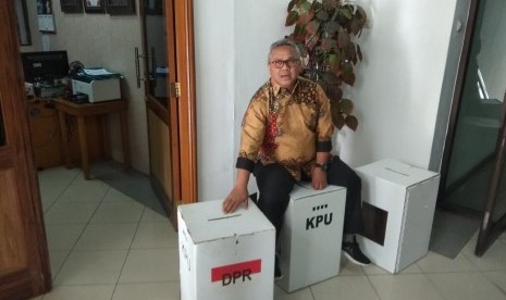 Ketua KPU, Arief Budiman, menduduki kotak suara untuk pemilu yang berbahan dasar karton kedap air, Senin (17/12). KPU menjelaskan latar belakang pemilihan bahan baku yang disebut kardus tersebut.