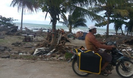 Situasi terkini di Jalan Raya Pantai Carita sekitar km 144, Karang Bolong, Anyer Cinangka, Serang, Banten, Senin (24/12) sore. Tampak puing-puing bekas bangunan yang terhempas sapuan gelombang tinggi pada Sabtu (22/12) malam lalu. Jalan sudah dapat dilalui, meskipun proses pembersihan dengan kendaraan alat berat dan para petugas masih dilakukan.