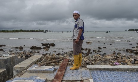 Warga berdiri di atas bekas rumahnya yang hancur diterjang gelombang tsunami Selat Sunda di Kecamatan Sumur, Pandeglang, Banten, Selasa (25/12/2018).