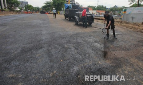 Pekerja melakukan proses 'prime coat' pada urukan tanah sebelum diaspal di lokasi jalan ambles di Jalan Raya Gubeng, Surabaya, Jawa Timur, Rabu (26/12/2018).