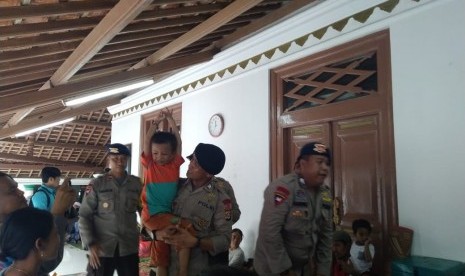 Personil Brimob Polda Banten melakukan pemulijan trauma kepada anak-anak pengungsi di Desa Pagedongan, Pandeglang, Banten. Kamis (27/12). 