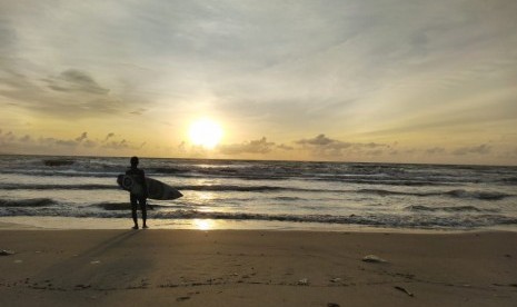 Seorang pemuda berselancar di Pantai Carita, Pandeglang, Banten, sepekan setelah tsunami melanda pantai itu, Sabtu (29/12).