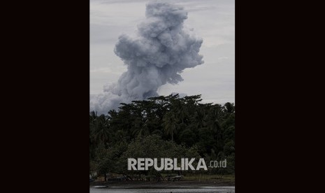 Warga beraktivitas dengan latar belakang erupsi Gunung Anak Krakatau di Pelabuhan Pulau Sebesi, Lampung Selatan, Lampung.