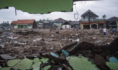 Warga berjalan di sisa-sisa bangunan yang rusak diterjang tsunami Selat Sunda di Sumur, Pandeglang, Banten, Kamis (3/1/2019). 