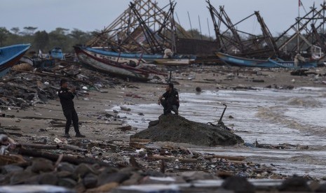 Warga memotret rekannya di antara puing-puing yang rusak karena tsunami Selat Sunda di Sumur, Pandeglang, Banten, Kamis (3/1/2019). 