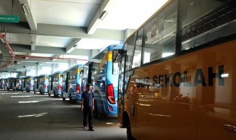 Warga melintas di samping deretan bus Trans Patriot yang terparkir, di Bekasi, Jawa Barat, Kamis (3/1/2019).