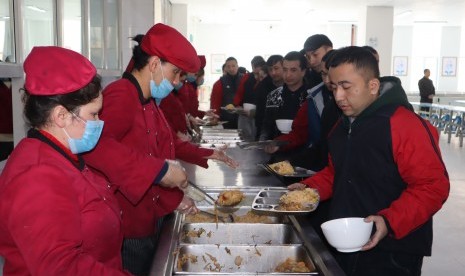 Para peserta didik kamp pendidikan vokasi etnis Uighur di Kota Kashgar, Daerah Otonomi Xinjiang, Cina, antre makan siang di kantin saat jam istirahat, Jumat (3/1/2019). 