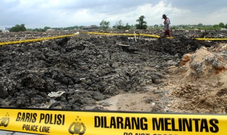 Warga melintas di dekat area lahan pembuangan pasir yang diduga mengandung limbah Bahan Beracun Berbahaya (B3), di kawasan Banjir Kanal Timur, Tarumajaya, Kabupaten Bekasi, Jawa Barat, Rabu (16/1/2019).