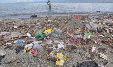 Seorang nelayan menjaring ikan di sekitar sampah yang memenuhi pantai di Palu, Sulawesi Tengah, Rabu (16/1/2019). 