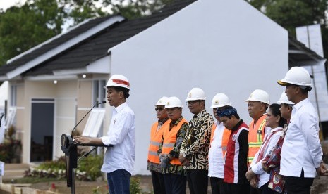 Presiden Joko Widodo (kiri) didampingi Ibu Negara Iriana Joko Widodo (ketiga kanan), Mensos Agus Gumiwang Kartasasmita (kanan), Menteri PUPR Basuki Hadimuljono (keenam kanan), Gubernur Jawa Barat Ridwan Kamil (keempat kiri) dan Dirut BTN Maryono (ketiga kiri) menyampaikan sambutan saat peletakan batu pertama perumahan Persatuan Pencukur Rambut Garut (PPRG) di Garut, Jawa Barat, Sabtu (19/1/2019). 