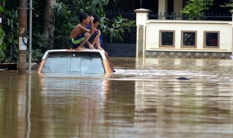 Sejumlah anak duduk di atas mobil yang tergenang air di Perumahan Bumi Bung Permai, Makassar, Sulawesi Selatan, Kamis (24/01/2019).