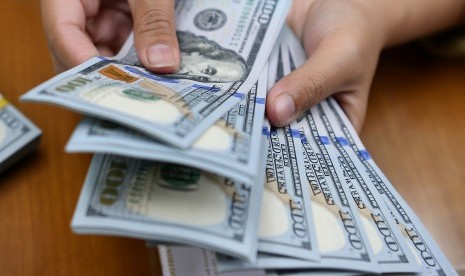 Karyawan menghitung mata uang dolar Amerika Serikat di gerai penukaran mata uang asing. ilustrasi