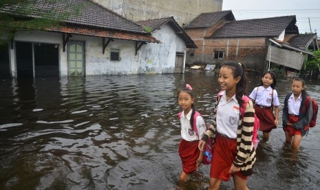 Sejumlah siswa melewati jalan yang terdampak banjir di Desa Gendok, Jati, Kudus, Jawa Tengah, Selasa (29/1/2019). 