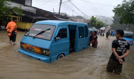 Warga mendorong angkot yang mogok akibat tergenang banjir di Kelurahan Mahawu, Manado, Sulawesi Utara, Jumat (1/2/2019).