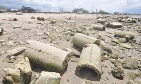 Pengendara melintas di samping tanggul pengaman pantai yang ambruk akibat gempa dan tsunami di Kawasan Penggaraman, Palu, Sulawesi Tengah, Senin (4/2/2019).