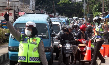 Polisi mengatur lalu lintas untuk mengurai antrean kendaraan menuju kawasan Puncak, Gadog, Bogor, Jawa Barat, Selasa (5/2/2019).