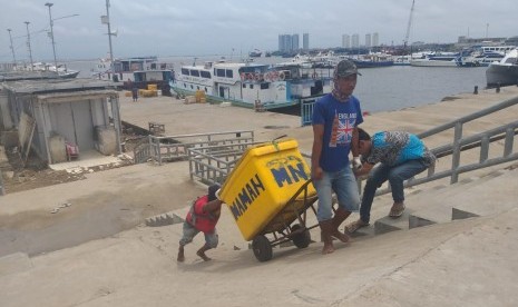 Pekerja bongkar muat ikan melintasi jembatan tanggul laut di Pelabuhan Kali Adem, Muara Angke, Jakarta Utara, Senin (12/2). 