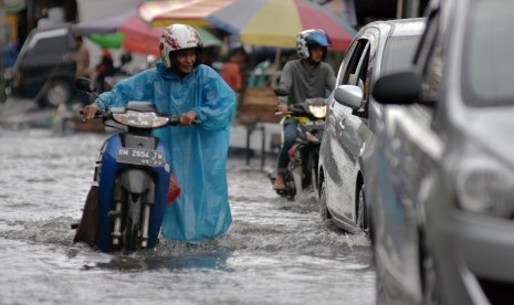 Seorang warga mendorong motornya yang mogok saat melewati banjir yang menggenangi Jalan M. Yatim Kota Pekanbaru, Riau, Kamis (14/2/2019).