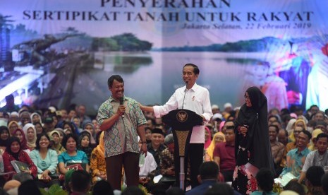 President Joko Widodo (center) hands over land certificates to some three thousand residents at the Pasar Minggu Sports Stadium in South Jakarta on Friday.