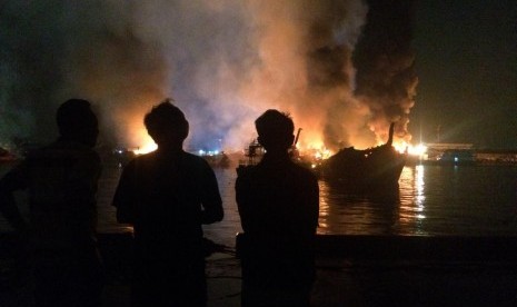 Kebakaran Kapal: Warga melihat sisa-sisa kapal yang terbakar di Pelabuhan Muara Baru, Jakarta Utara, Sabtu (23/2) malam.