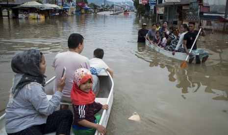 Warga menggunakan perahu melintasi banjir di Jalan Raya Dayeuhkolot, Kabupaten Bandung, Jawa Barat, Kamis (7/3/2019).