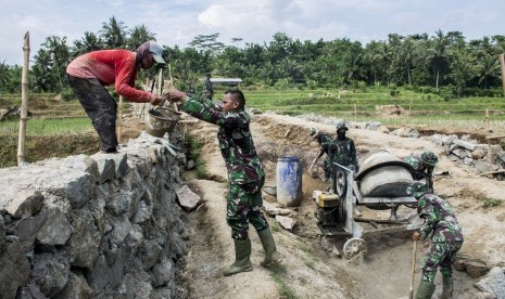 Sejumlah anggota TNI dan warga bergotong royong membangun jembatan antar Desa saat program Tentara Manunggal Membangun Desa (TMMD) di Desa Purwasedar, Ciracap, Kabupaten Sukabumi, Jawa Barat, Jumat (8/3/2019).