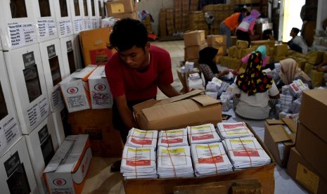 Pekerja mengemas kertas suara untuk didistribusikan.