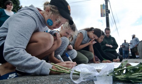 Warga menulis pesan di dekat bunga yang diletakkan di depan Masjid Wellington, Kilbirnie, Wellington, Selandia Baru, Sabtu (16/3/2019).