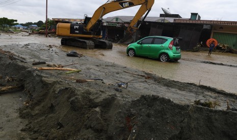 Sebuah alat berat mengevakuasi mobil yang terseret banjir bandang di Sentani, Jaya Pura, Papua, Senin (18/3/2019).