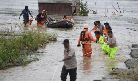 Tim SAR Gabungan mendorong perahu karet yang memuat jenazah korban banjir bandang Sentani yang di temukan di sekitar perumahan Gajah Mada di Sentani, Jaya Pura, Papua, Selasa (19/3/2019).