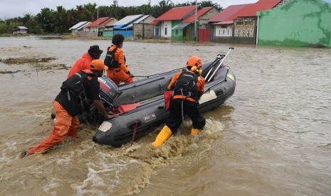 Anggota Basarnas mendorong perahu karet ketika melakukan evakuasi jenazah korban banjir bandang Sentani yang di temukan di sekitar perumahan Gajah Mada di Sentani, Jaya Pura, Papua, Selasa (19/3/2019). 