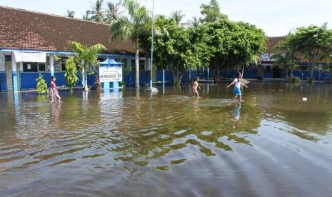 Siswa melintasi banjir di halaman SDN Wonoasri 01, Tempurejo, Jember (ilustrasi-