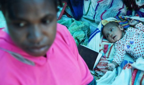 Seorang ibu pengungsi banjir bandang Sentani dan anaknya berada di dalam tenda darurat yang mereka dirikan di Bukit Harapan, Sentani, Jaya Pura, Papua, Rabu (20/3/2019). 