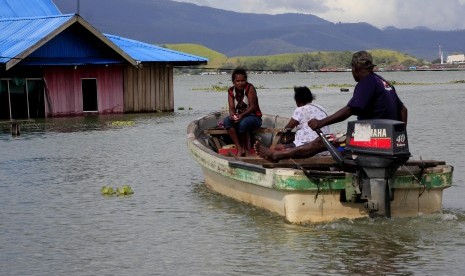 Warga menggunakan perahu menuju rumahnya yang terendam banjir akibat meluapnya Danau Sentani dampak dari banjir bandang Sentani di Kampung Yoboi, Danau Sentani, Sentani, Jaya Pura, Papua, Jumat (22/3/2019).