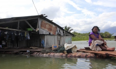 Seorang warga duduk di halaman rumahnya yang terendam banjir akibat meluapnya Danau Sentani dampak dari banjir bandang Sentani di Kampung Yoboi, Danau Sentani, Sentani, Jaya Pura, Papua, Jumat (22/3/2019).