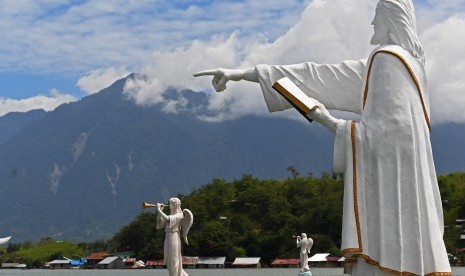 Kondisi patung Yesus dengan latar pemukiman warga yang terndam banjir dan longsoran di Gunung Cycloop di Danau Sentani, Jayapura, Papua, Ahad (24/3/2019). 