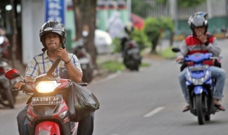 Sejumlah pengendara merokok sambil mengendarai sepeda motor, di Padang, Sumatera Barat, Jumat (29/3/2019). 