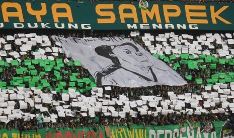 Suporter Persebaya Surabaya mengheningkan cipta dengan membentangkan spanduk bergambar Eri Irianto saat pertandingan semifinal Piala Presiden 2019 leg pertama antara Persebaya Surabaya melawan Madura United di Stadion Gelora Bung Tomo, Surabaya, Jawa Timur, Rabu (3/4/2019).