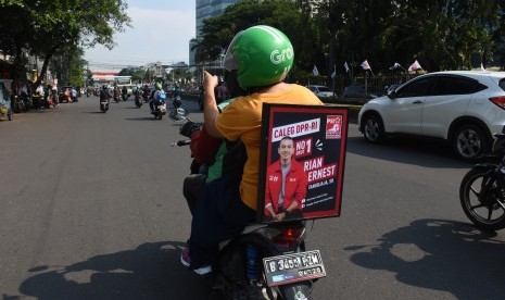 Sebuah poster salah satu caleg terpampang pada kendaraan ojek daring saat melintas di kawasan Senen, Jakarta, Kamis (4/4/2019).