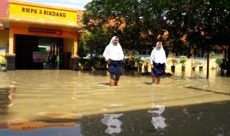 Para siswa SMPN 3 Sindang mengerjakan USBN dengan kondisi ruang kelas yang terendam banjir, Selasa (9/4). Memasuki hari kedua, banjir akibat luapan sungai Cimanuk di Kabupaten Indramayu semakin meluas.